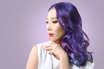Beautiful Asian woman with unusual hair on color background