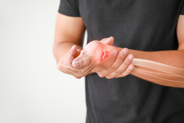 Young man with broken wrist suffering from pain on white background, closeup