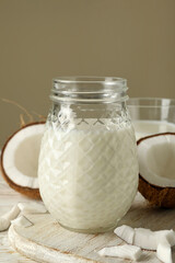 Board with fresh coconut and coconut milk on wooden background