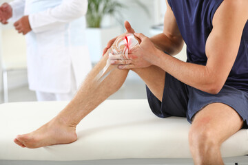 Young man with broken leg visiting doctor in clinic