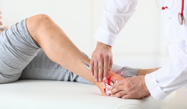 Doctor examining man with broken leg in clinic