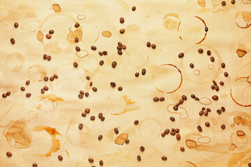 Brown coffee stains and beans on light background