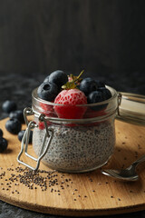 Board with jar of delicious chia pudding on black smokey table