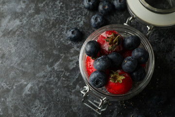 Jar with delicious chia pudding on black smokey table