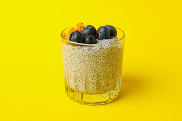 Glass of delicious chia pudding on yellow background
