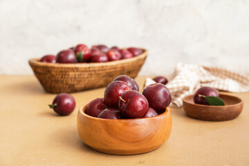 Bowl with fresh ripe plums on table