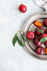 Plate with  fresh ripe plums on  light background
