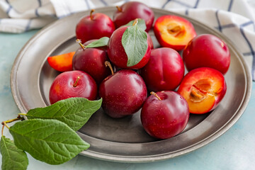 Naklejka na ściany i meble Plate with fresh ripe plums on table