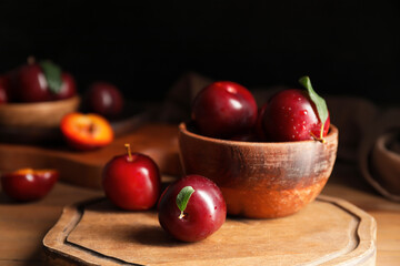 Naklejka na ściany i meble Bowl with fresh ripe plums on wooden table