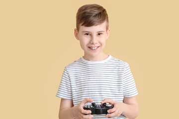 Cute boy with game pad on color background