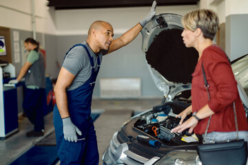 African American mechanic talking to a customer at auto repair shop.