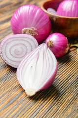 Bowl with fresh raw onion on wooden background