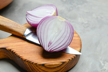 Fresh raw onion and knife on gray background