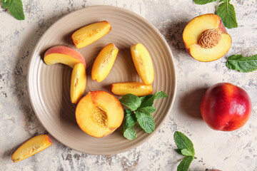 Plate with cut ripe peaches on table