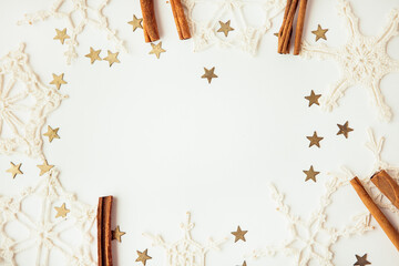 White snowflakes, gold stars and cinnamon sticks on the white background, copy space for text