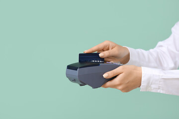 Woman with credit card and payment terminal on color background