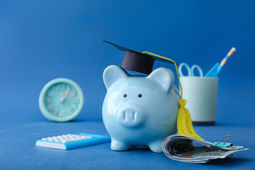 Piggy bank with graduation hat and money on color background. Tuition fees concept