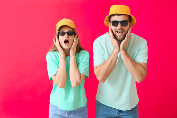 Surprised couple with stylish sunglasses on color background