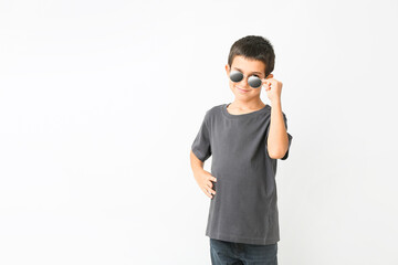 Cute boy wearing stylish sunglasses against white background