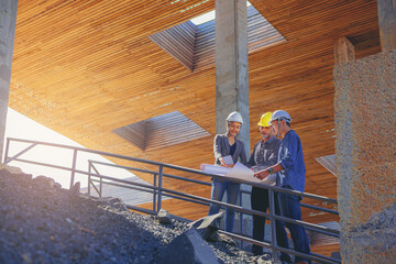 Structural engineer and architect working with blueprints discuss at the stairway, outdoors...