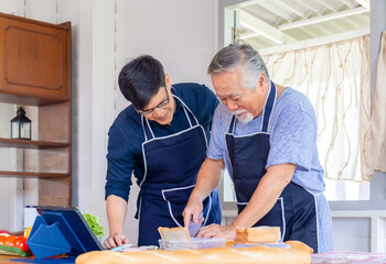 Cheerful senior asian father and middle aged son cooking together at kitchen, Happiness asian family concepts