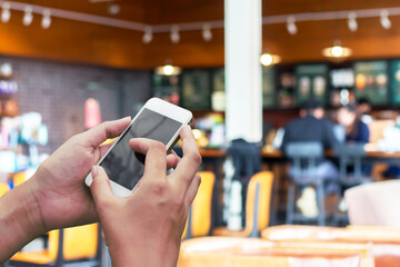 Uses smart phone on blur shop cafe blur.