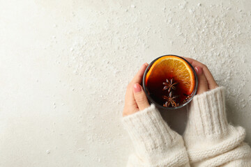 Female hands hold glass of mulled wine on white background with snow