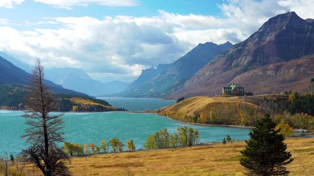 Middle Waterton Lake lakeshore in autumn foliage season sunny day morning. Blue sky, white clouds over mountains in the background. Landmarks in Waterton Lakes National Park, Alberta, Canada.