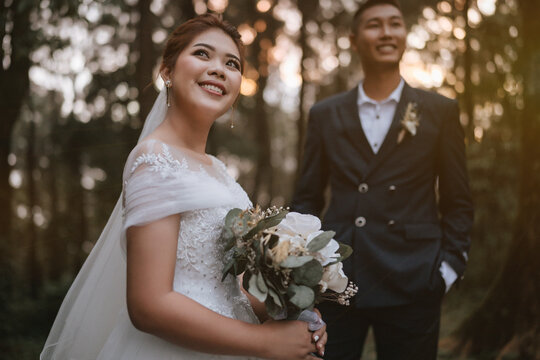 The newlyweds happy in the atmosphere of the pine forest, looking and feeling warm.