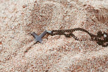 a cross with a chain lies in the sand