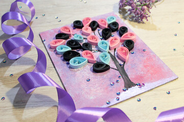 A beautiful bright tree made by hand, a paper quilling panel with a purple ribbon
