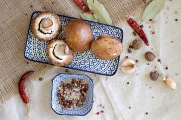 Fresh dark royal champignons, on a rough linen background with chili and spices, close up