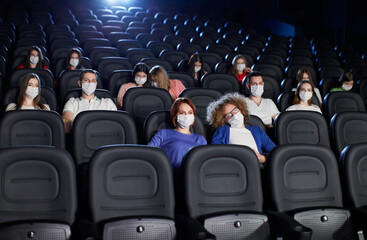 Young audience wearing face masks in cinema.