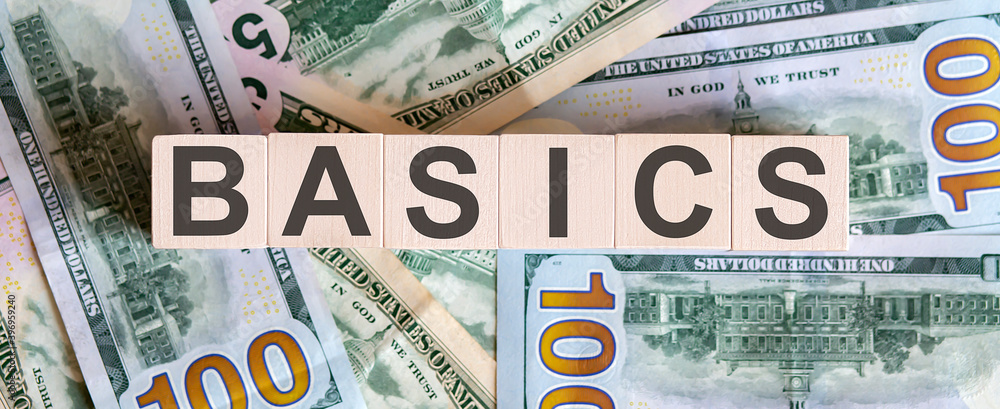 Poster concept words basics on wooden blocks on a beautiful background from dollar bills.