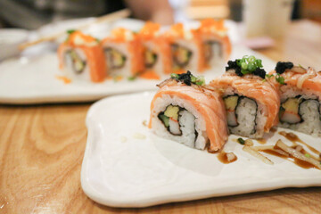 burn Salmon on sushi rolls on white plate