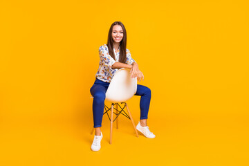 Fototapeta na wymiar Photo portrait full body view of woman resting hands on chair back sitting isolated on bright yellow colored background