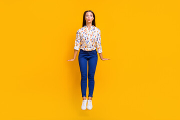 Full length photo portrait of woman sending air kiss jumping up isolated on bright yellow colored...