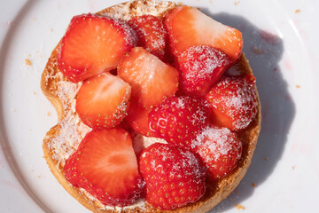 A rusks with strawberries with sugar on a white plate.Seen from above. Selective focus