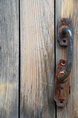 An old rusty iron handle on a wooden door. The concept of vintage