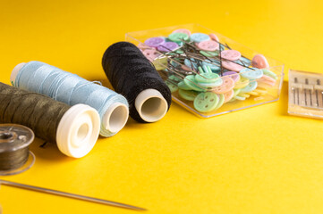 Sewing supplies on a yellow background. Thread, needles, and pins in the container. Set for...