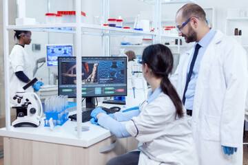 Group of scientist analysing genetic material. Team of researchers doing pharmacology engineering in sterile laboratory for healthcare industry with african assistant in the background.