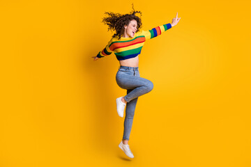 Fototapeta na wymiar Full length photo of energy jumping lady wearing casual colorful sweater dancing pointing looking empty space isolated yellow color background
