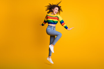 Fototapeta na wymiar Full length photo of funny jumping woman dressed casual colorful sweatshirt looking empty space isolated yellow color background