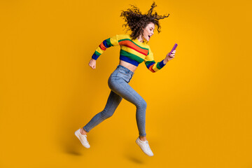 Fototapeta na wymiar Profile full size photo of cheerful pretty wavy hair girl run read message wear sweater jeans sneakers isolated on yellow background