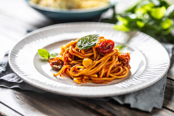 Spaghetti with tomato puree, chery tomaties and a basil on the top