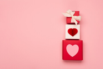 Paper hearts and festive gift boxes on pastel pink background. Valentines day concept.