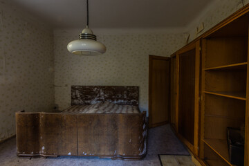 bedroom with a lamp and a moldy wooden bed in a house