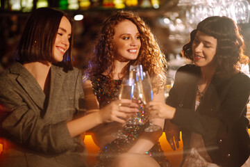 Three young Woman with champagne glasses at night club.  Women friends drinking champagne  in the bar. Party, celebration, friends, bachelorette party, birthday, winter holidays concept.