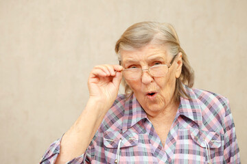 An elderly woman is surprised and adjusts her glasses