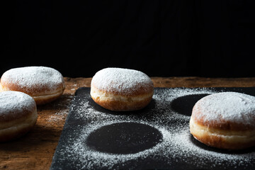 Traditional German fried donuts with no hole, so called Krapfen or "Berliner Pfannkuchen" sprinkled with powdered sugar and filled with jam or chocolate. donuts in preparation